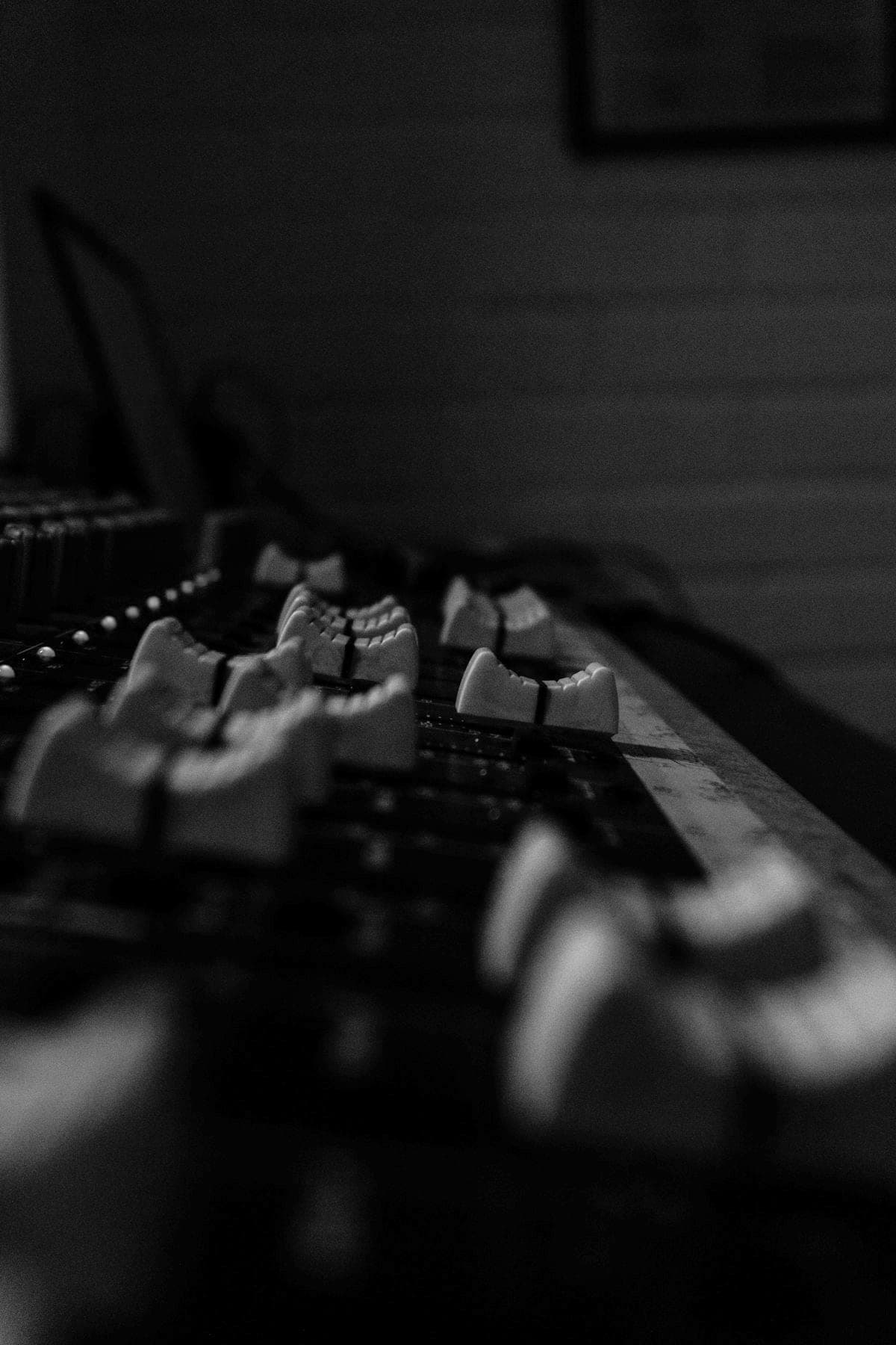 Close-up of mixing-console faders in a dark room.