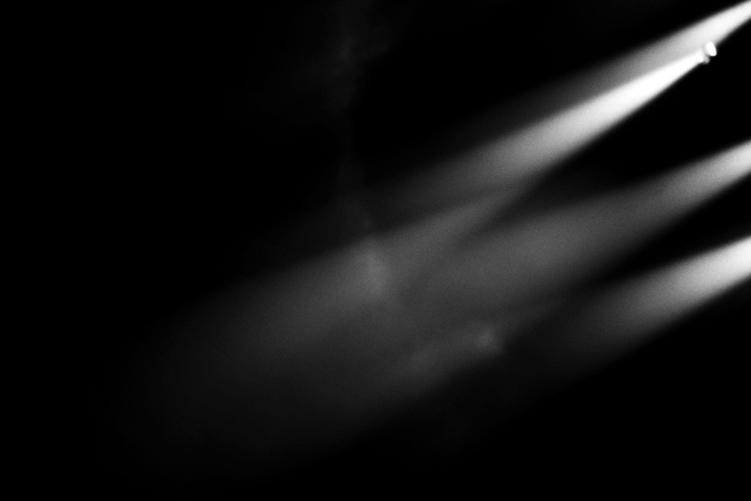Stage light beams slanting through smoke into a dark void.